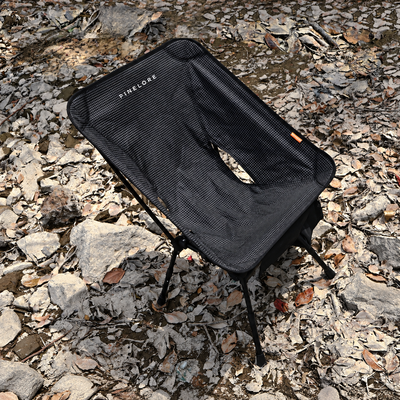 PINELORE black grid-pattern folding camp chair with adjustable legs, shown outdoors